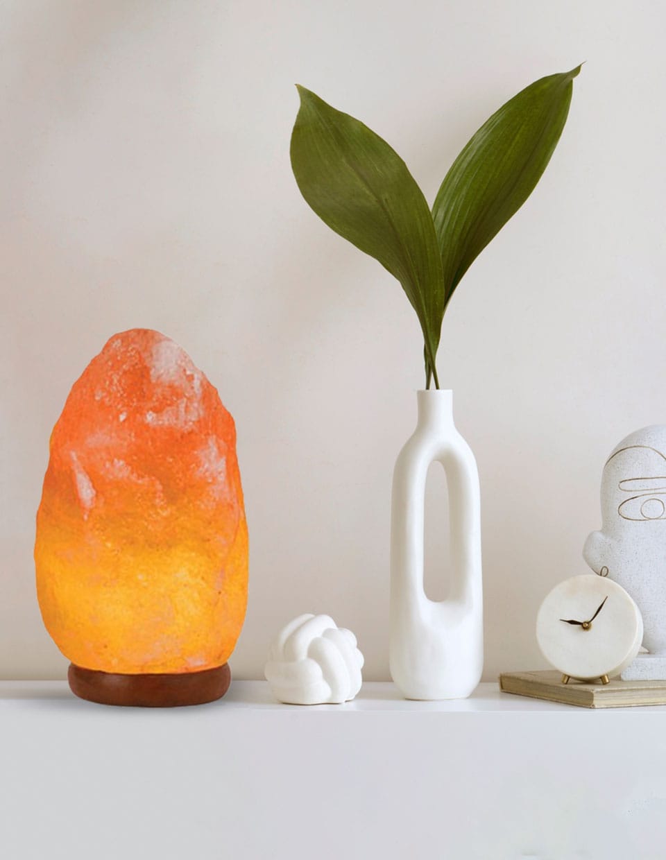 Premium Himalayan Salt Rock Lamp glowing warmly on a modern white shelf beside minimalist décor, sourced from a top Himalayan salt exporter from Pakistan.